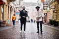 Two fashion black men walking on street. Fashionable portrait of african american male models. Wear suit, coat and hat Royalty Free Stock Photo