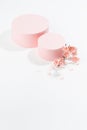 Two fashion spring cylinder podiums mockup with twig of gentle pink sakura flowers, petals in sunlight with shadow