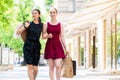 Two fashionable young women walking in the city during shopping