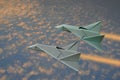 Two fast jet planes fly over golden clouds in early morning