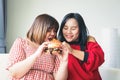 Two fat women in Asians eat large hamburgers.