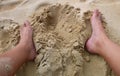 Two feet around hole in the beach sand Royalty Free Stock Photo