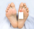 Two feet of a dead body, with blank sign Royalty Free Stock Photo