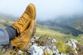 Two feet in yellow hiking boots against the backdrop of a mountain landscape