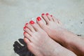 Two feet of a young girl with red toenails lying on the beach sand Royalty Free Stock Photo