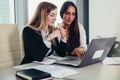 Two female accountants working together on financial report using laptop sitting at desk in account department Royalty Free Stock Photo