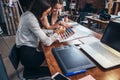 Two female architects working together using color swatches sitting at desk with laptop, graphic tablet in design studio Royalty Free Stock Photo