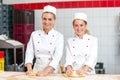 Two female bakers in bakery kneading dough at bakery