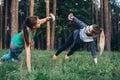 Two female buddies doing partner side plank giving high five while training in the forest