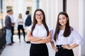 Two female business collegues standing next to each other in an office in front of business team Royalty Free Stock Photo