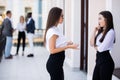 Two female business collegues standing next to each other in an office in front of business team Royalty Free Stock Photo