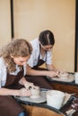 Two female ceramic artists in apron using clay material working in potter studio. Evening freelance distance learning Royalty Free Stock Photo