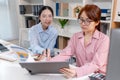 Two female colleagues discussing business reports together in a modern office environment, representing teamwork, data analysis, Royalty Free Stock Photo