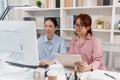 Two female colleagues discussing business reports together in a modern office environment, representing teamwork, data analysis, Royalty Free Stock Photo