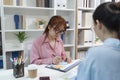 Two female colleagues discussing business reports together in a modern office environment, representing teamwork, data analysis, Royalty Free Stock Photo