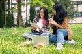 Two female college students are sitting on the grass in a campus park, discussing work outdoors Royalty Free Stock Photo