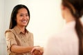 Two female coworkers giving hands greeting