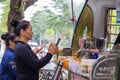 Two female customers use smartphone to pay their breakfast at a street booth with Qr code