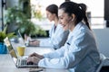 Two female doctor making video call with laptop while talking with earphone sitting in the consultation