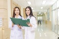 Two female doctors discussed together about a patient case with clipboard and stood