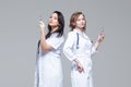 Two female doctors standing back-to-back hold ready-to-inject syringes Royalty Free Stock Photo