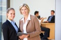 Two Female Executives Using Tablet Computer With Office Meeting In Background Royalty Free Stock Photo