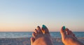 Two female feet with painted nails against the backdrop of the sea and sand Royalty Free Stock Photo