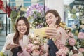 Two female florists demonstrate flower arrangements via online live streaming. Royalty Free Stock Photo