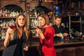 Two female friends are in the bar for a drink and talk. The woman with talks near the ear of the friend Royalty Free Stock Photo