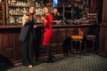 Two female friends are in the bar for a drink and talk. The woman with talks near the ear of the friend Royalty Free Stock Photo