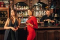 Two female friends are in the bar for a drink and talk. The woman with talks near the ear of the friend Royalty Free Stock Photo