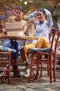 Two female friends enjoy the content of a laptop while having a drink at the bar. Leisure, bar, friendship, outdoor Royalty Free Stock Photo
