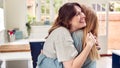 Two Female Friends Greeting And Hugging In Kitchen At Home Royalty Free Stock Photo