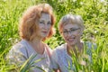 Two female friends having fun on nature. Chubby and slim middle-aged women pensioners in a green field
