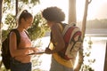 Two Female Friends With Map And Backpacks On Vacation Hiking By Lake At Sunset Together Royalty Free Stock Photo