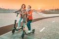 Female friends ride modern rented electric scooters through the streets of the city. Transport and lifestyle and friendships