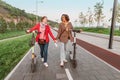 Female friends ride modern rented electric scooters through the streets of the city. Transport and lifestyle and friendships