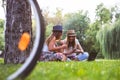 Two female friends sitting on the grass, talking and using laptop Royalty Free Stock Photo