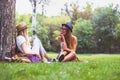 Two female friends sitting on the grass, talking Royalty Free Stock Photo