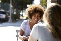 Two female friends sitting at a table outside a cafe Royalty Free Stock Photo