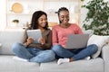 Two female friends spending time at home, using gadgets