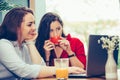 Two female friends using laptop and drinking coffee together Royalty Free Stock Photo