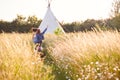 Two Female Friends Walking Pulling Trolley Through Field Towards Teepee On Summer Camping Vacation