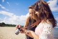 Two female friends watching photos on camera on beach