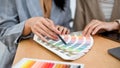 Two female graphic designers are reviewing the colour on the colour swatches palette