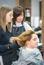 Two female hairstylists prepare long hair of a young woman making curls hairstyle in a beauty salon. Royalty Free Stock Photo