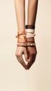 Two female hands clasped together adorned with satin ribbons and bracelets on neutral background Royalty Free Stock Photo