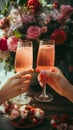 Two female hands holding glasses of champagne with bouquet of pink roses background. Royalty Free Stock Photo