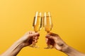 two female hands holding glasses of champagne on yellow background with copy space Royalty Free Stock Photo