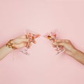 Two female hands holding wine glasses with colorful holiday confetti on pink background. Celebration, party and holidays Royalty Free Stock Photo